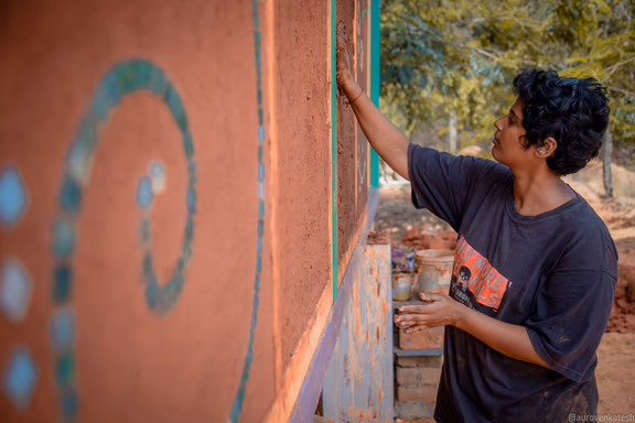 1 Nikki mud plastering a wall in Anitya community