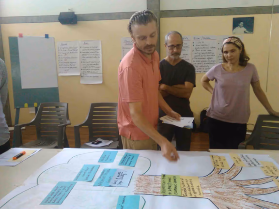 Angelo prepares an FAMC meeting, Lyle and Auralice look on