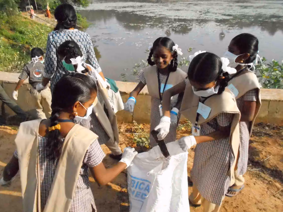 Students from Kuilapalayam cleaning trash near the temple pond