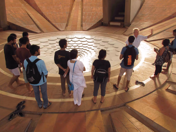 Gilles Guigan (with raised hand) speaks about the Matrimandir at the pond below